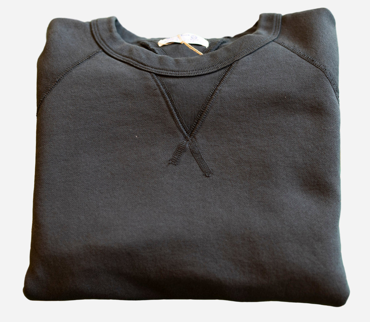 Folded black hoodie on a green cutting mat with grid lines