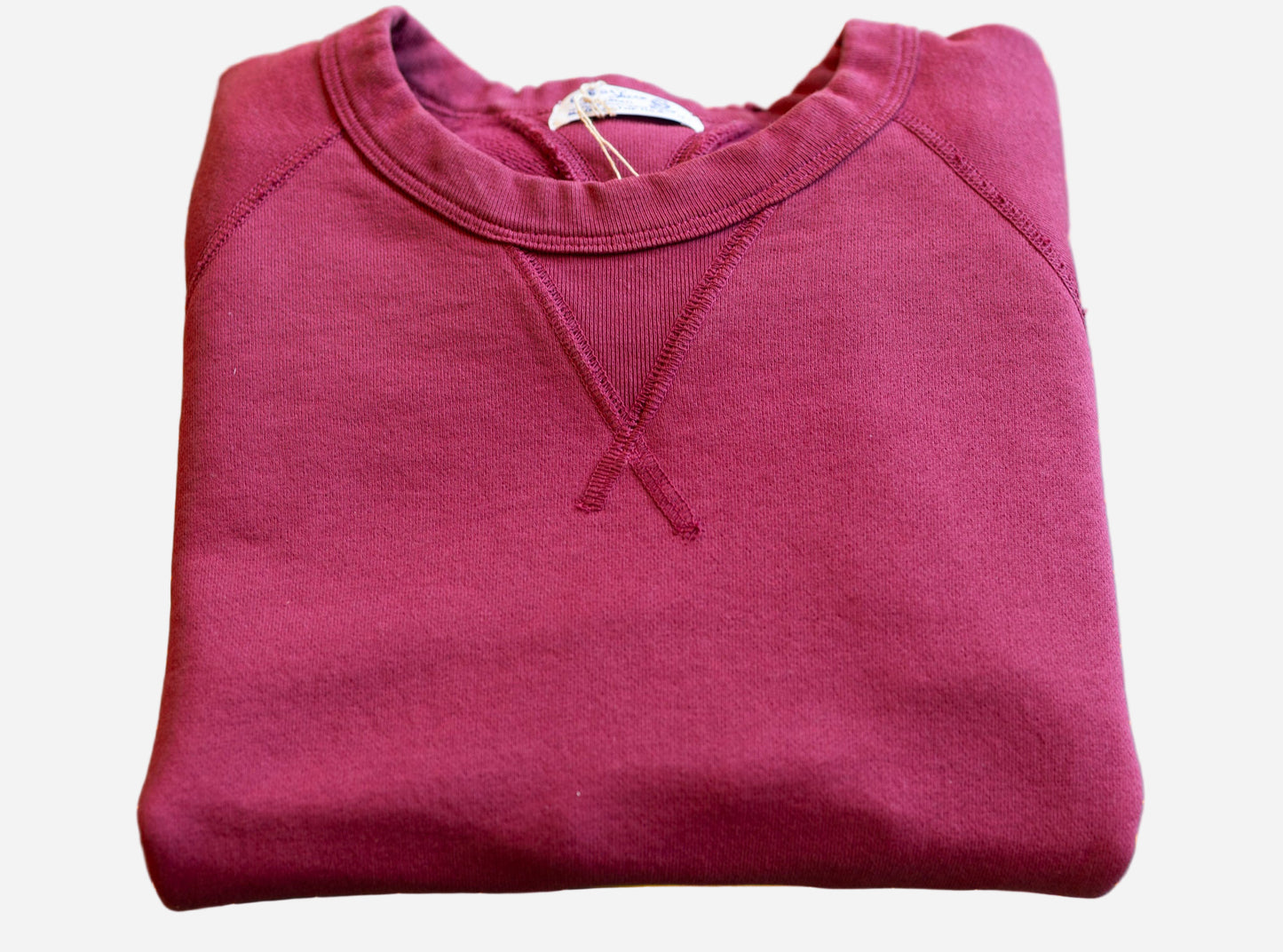 Folded maroon sweatshirt on a green cutting mat with yellow grid lines