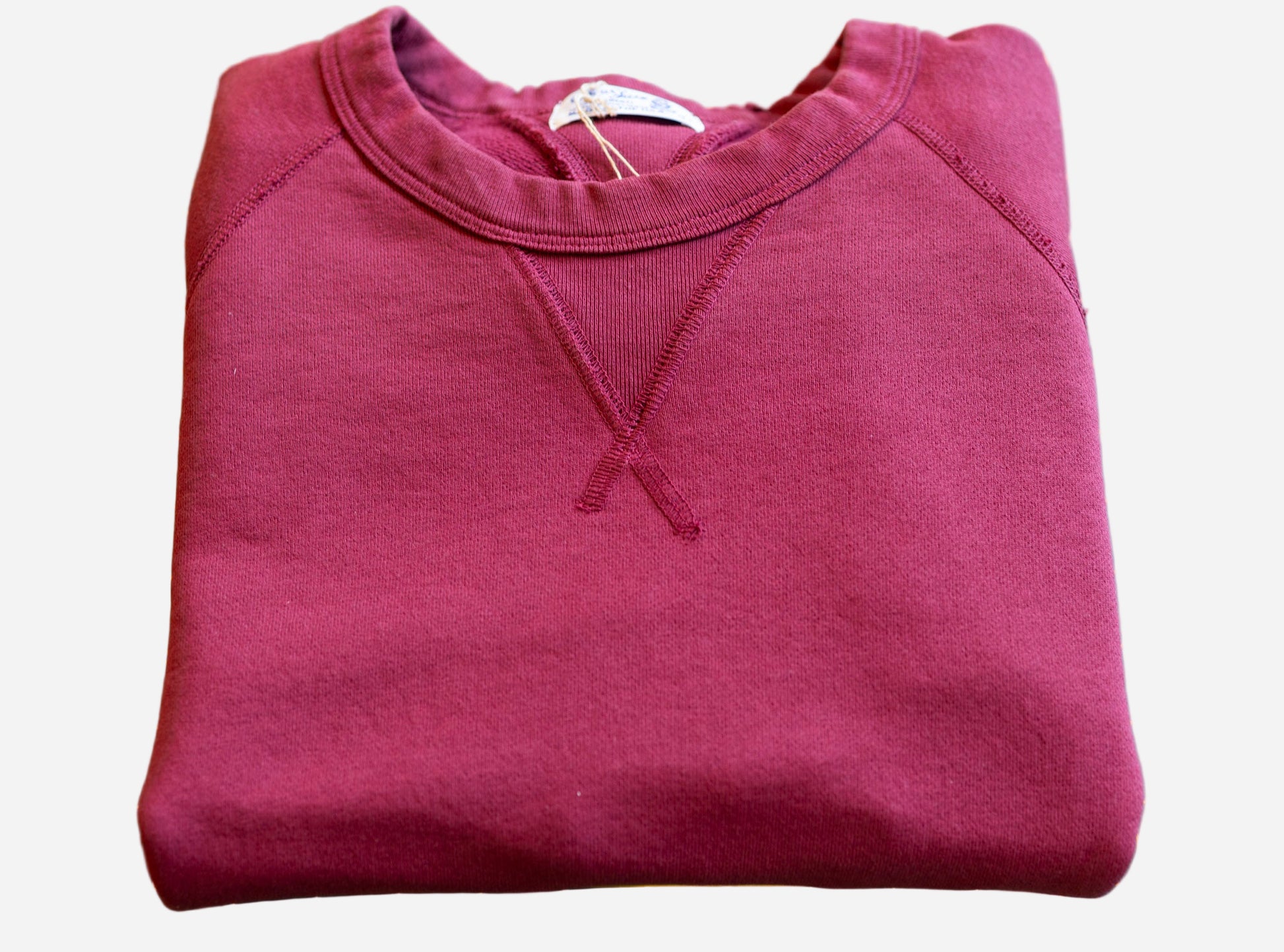 Folded maroon sweatshirt on a green cutting mat with yellow grid lines